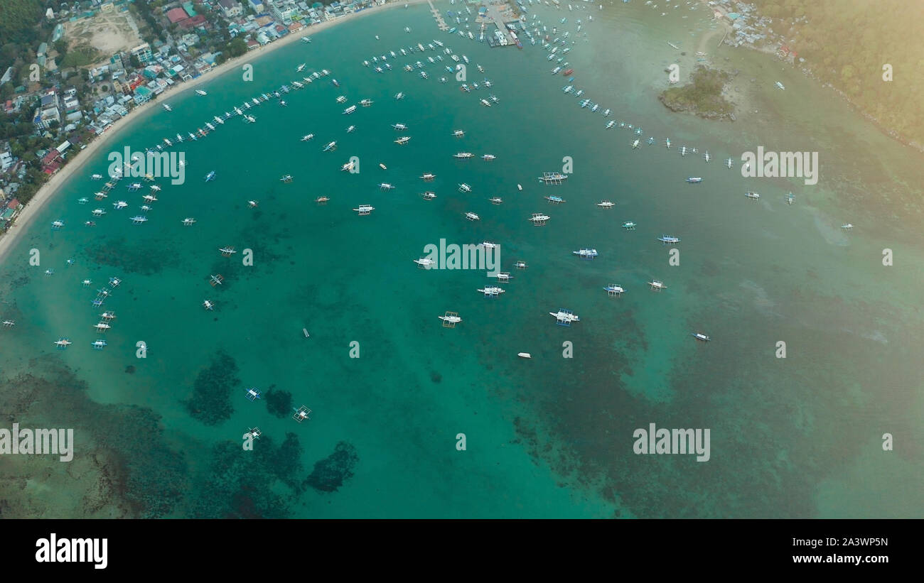 Muchos barcos en la laguna de color turquesa al atardecer. Seascape con Blue Bay y los barcos vista desde arriba. El nido, Palawan, Filipinas. tradicionales de madera filipina outrigger barco llamado una banca. Concepto de vacaciones de verano y viajes Foto de stock