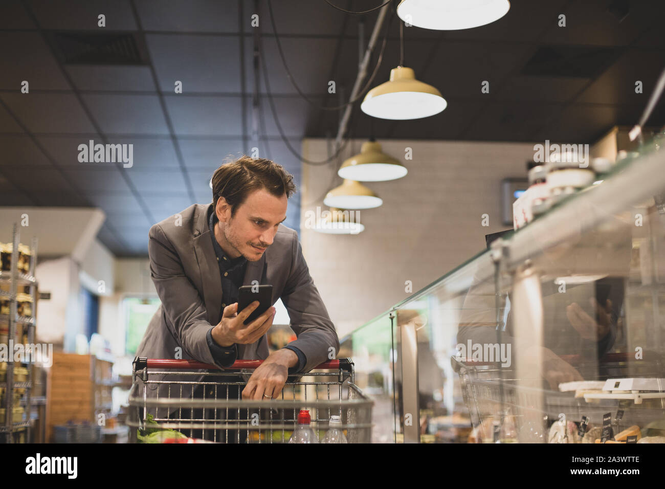 Shopper macho adulto en el deli contador en una tienda de ultramarinos Foto de stock