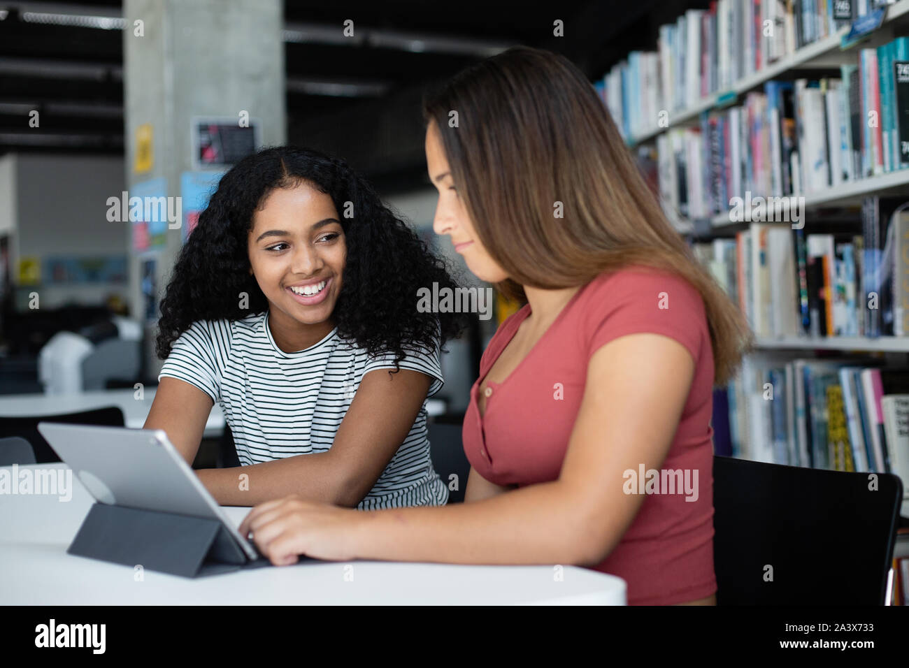 High school alumnas estudiando con tableta digital en la biblioteca Foto de stock