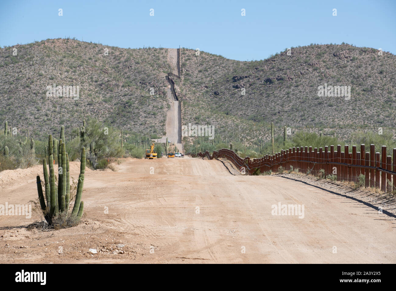 El original bolardo frontera muro siguiendo un camino de acceso a través del Monumento Nacional Organ Pipe Octubre 8, 2019 oeste de Lukeville, Arizona. Más de 100 cactus en peligro de extinción, incluyendo 76 sahuaros, han sido reubicadas para dejar espacio para el nuevo proyecto de la pared fronteriza a lo largo de la frontera México - Estados Unidos. Foto de stock