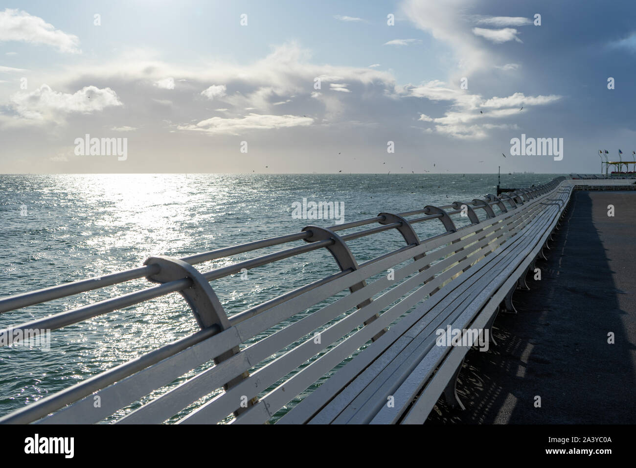 Bancos de madera blanca bordeando un muelle costera británica Foto de stock