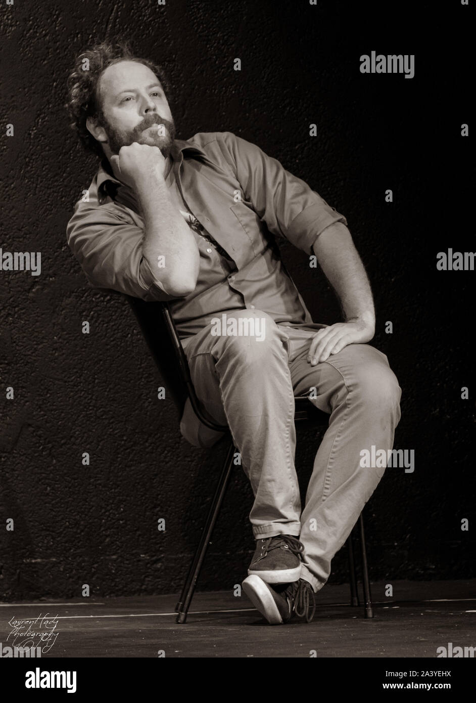 Hombre sentado en una silla, mirando hacia arriba, perdido en sus pensamientos Foto de stock