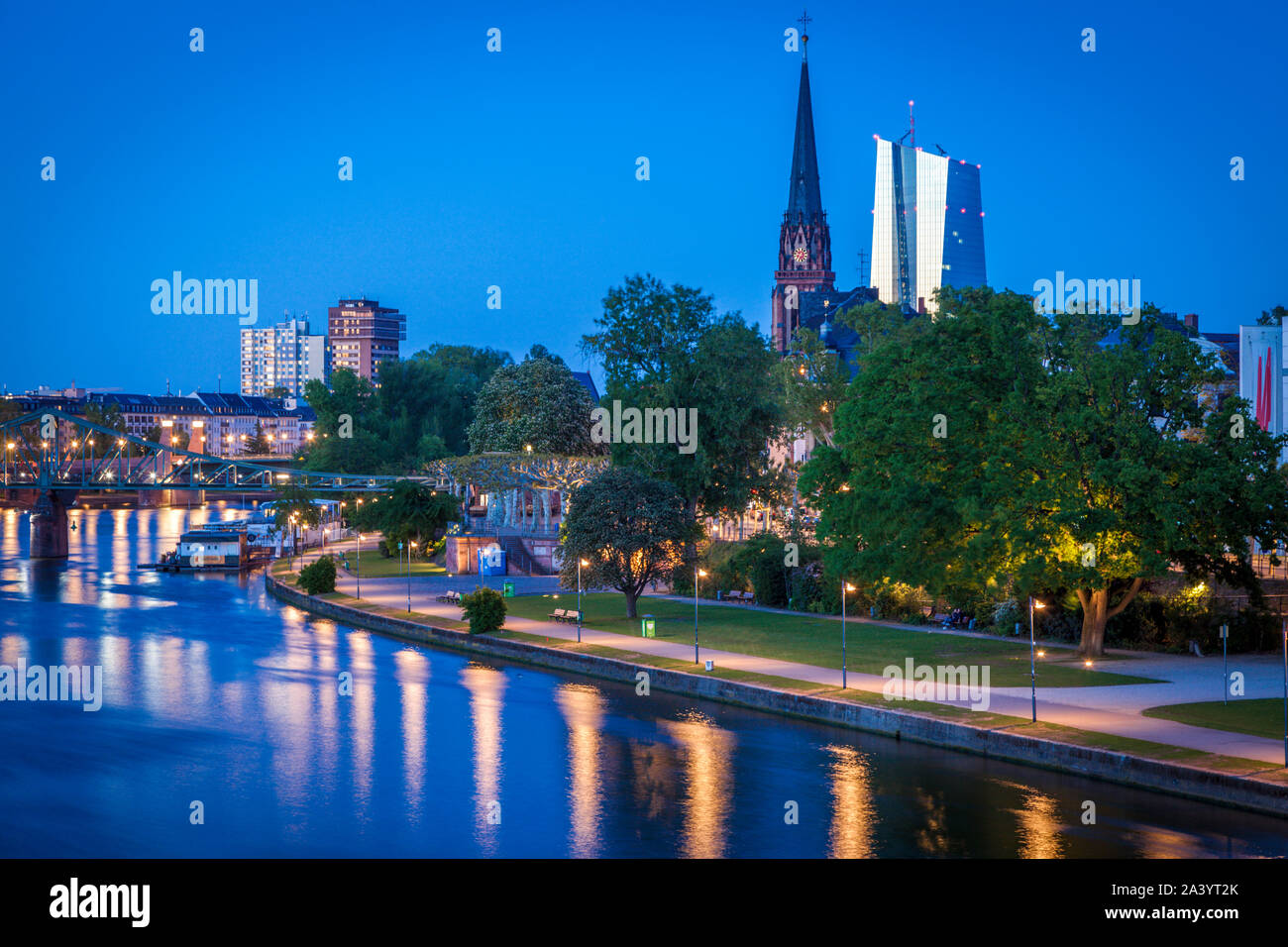 Iglesia y torres de oficinas por el río al atardecer en Frankfurt, Alemania Foto de stock