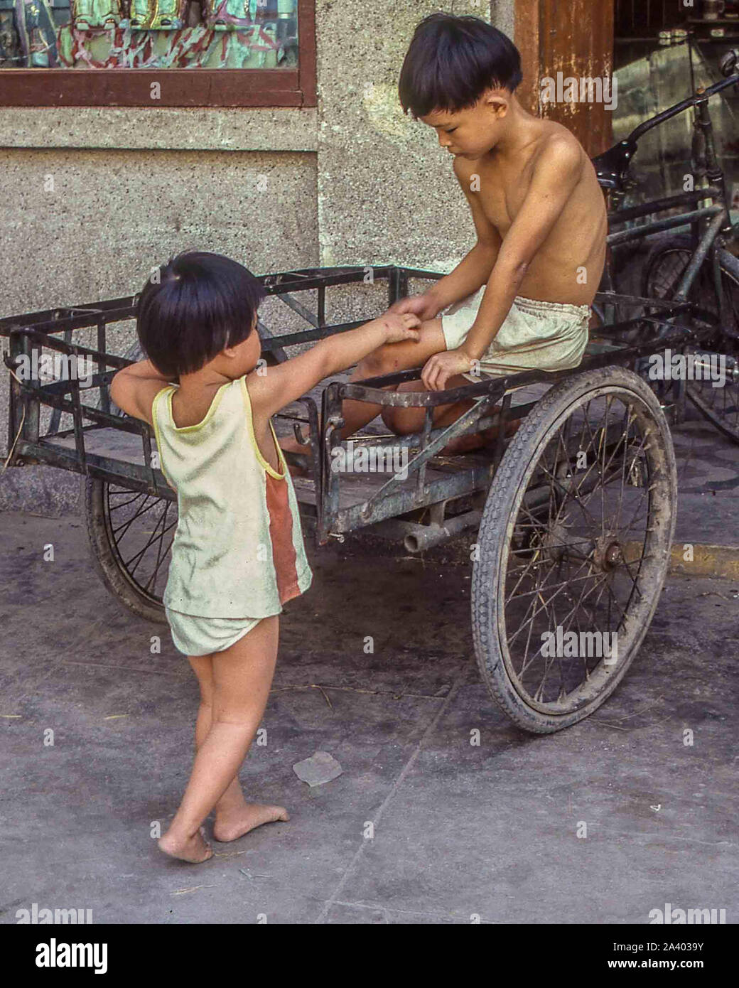 Shenzhen, Guangdong, China. 4 de agosto, 1981. En Shenzhen en 1981, dos  jóvenes chinos niños juegan en un triciclo. Una ciudad provincial, en el  sureste de China, que enlaza Hong Kong a