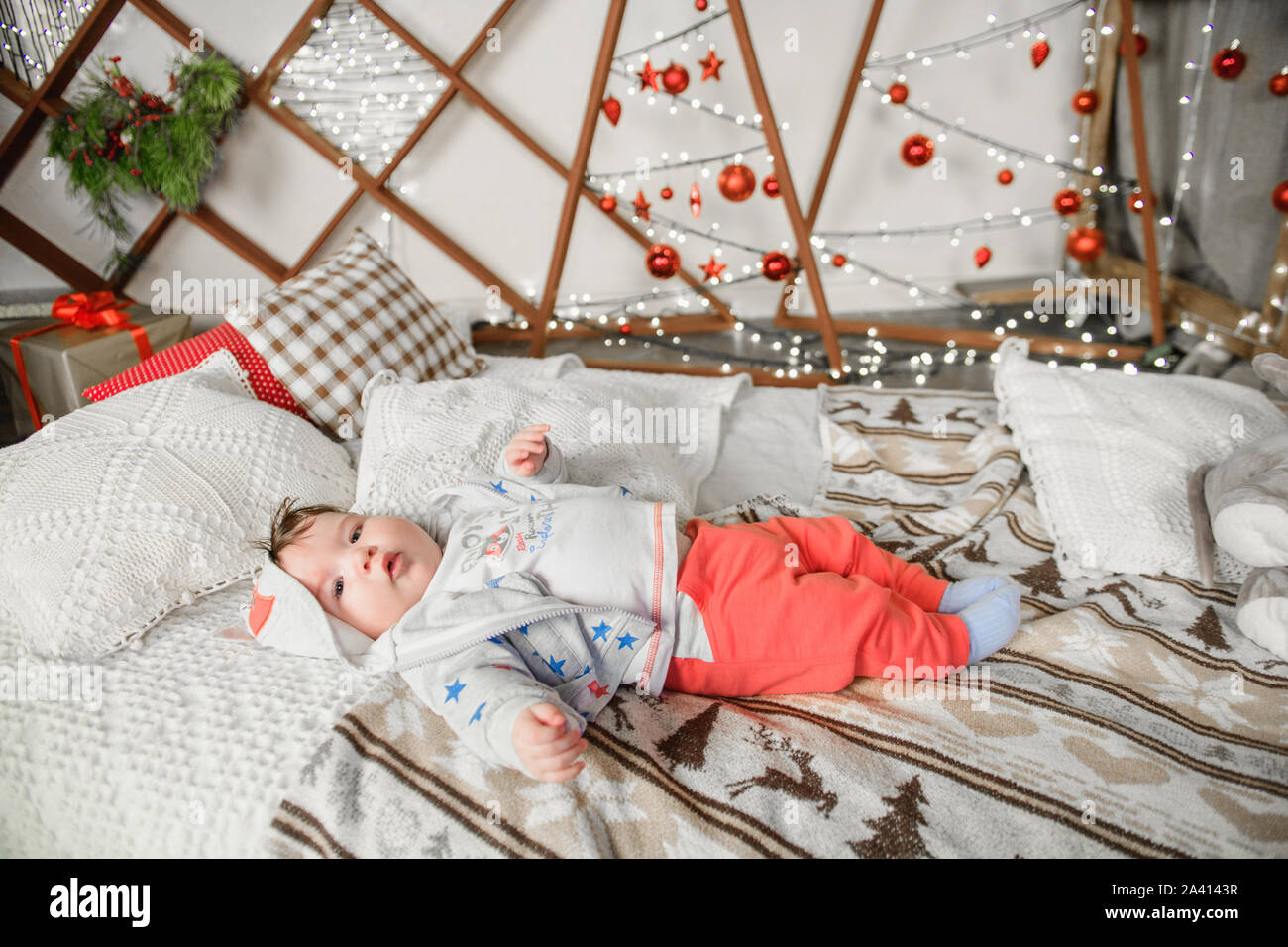 Un niño de 0 a 1 años está en la cama en un ajuste de Navidad. Feliz Año Nuevo y feliz Navidad Foto de stock