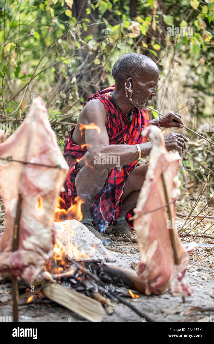Arusha, Tanzania, el 7º de septiembre de 2019: el hombre masai cocinando la carne sobre el fuego Foto de stock