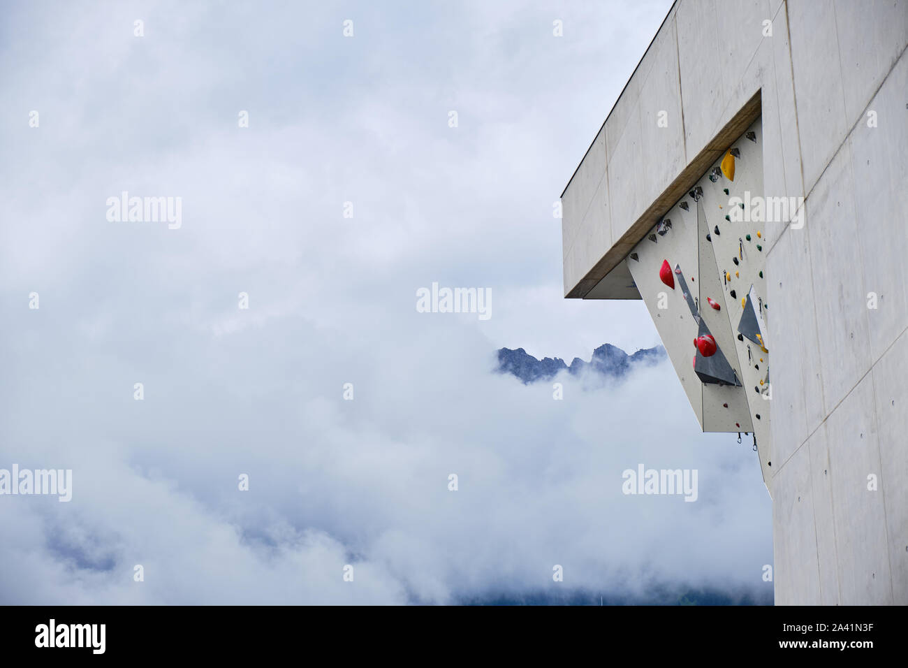 Suspensiones de plástico alto muro de escalada de plomo en Kletterzentrum Innsbruck (Centro de escalada) de Innsbruck, Austria, con nubes en el fondo, cubriendo el Foto de stock