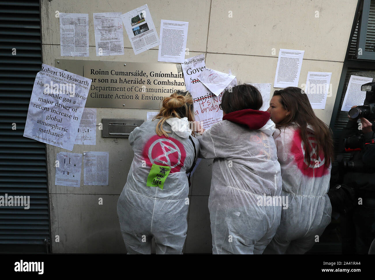 Extinción rebelión (XR) manifestantes wallpaper el frente del Departamento de Comunicaciones, en Acción por el clima y el Medio Ambiente, Dublín, con páginas de ciencia detallando el impacto climático de fracked gas. Foto de stock