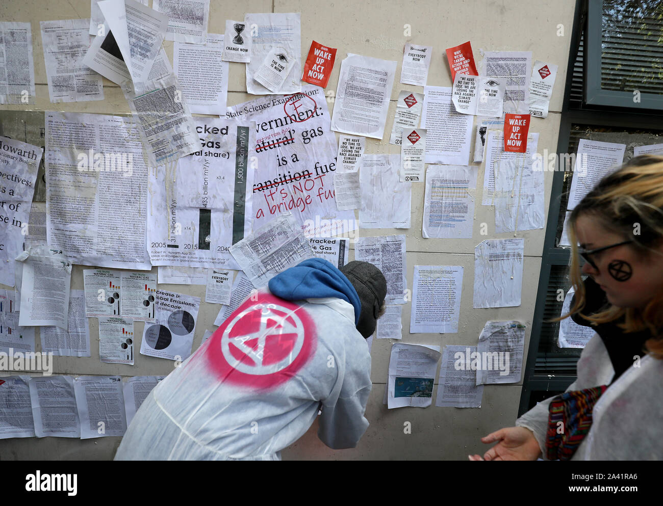 Extinción rebelión (XR) manifestantes wallpaper el frente del Departamento de Comunicaciones, en Acción por el clima y el Medio Ambiente, Dublín, con páginas de ciencia detallando el impacto climático de fracked gas. Foto de stock