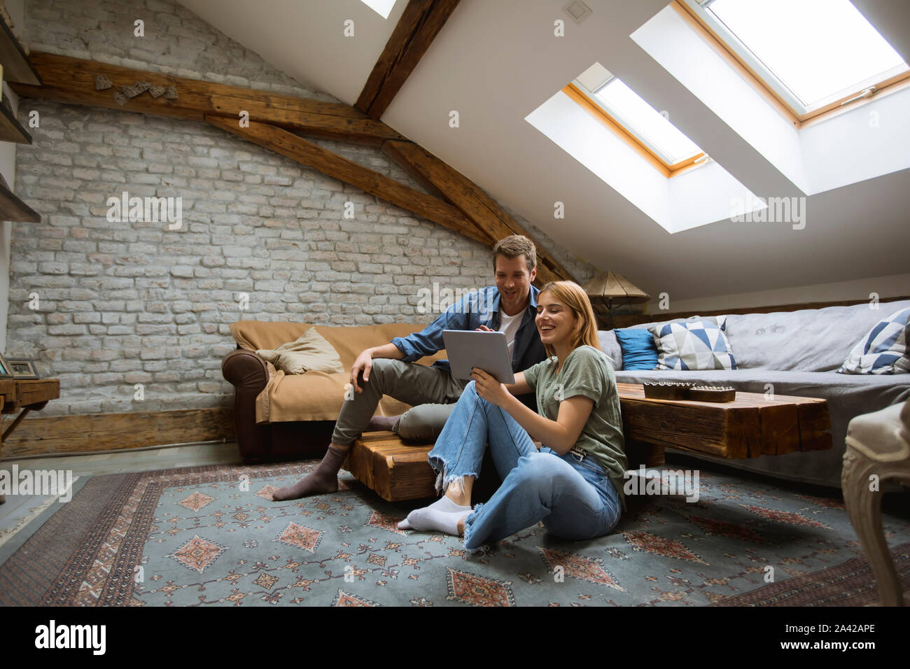 Feliz pareja joven con tablet sentados en el suelo en casa Foto de stock
