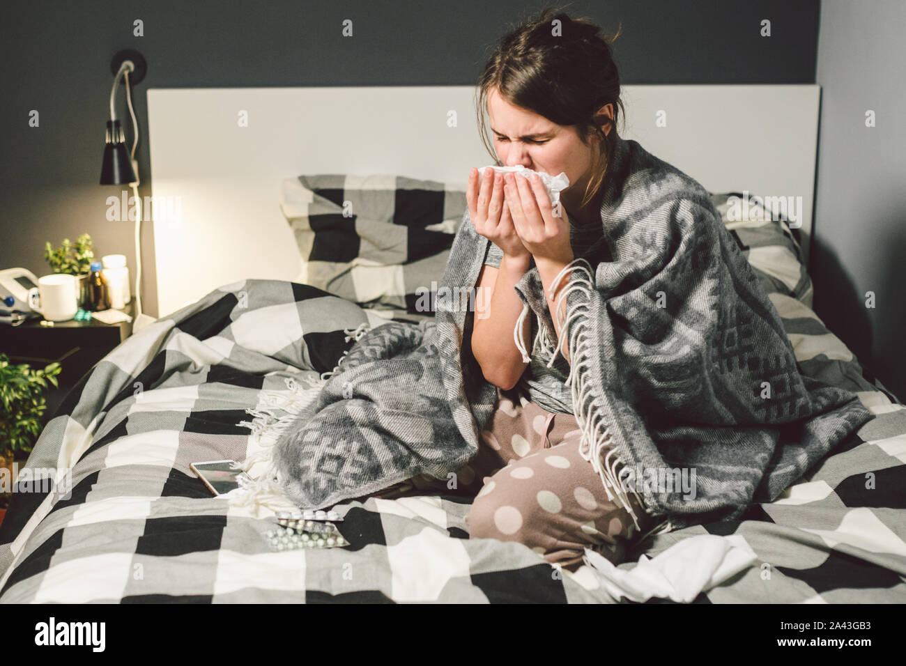 Mujer enferma con secreción nasal, sentada en la cama. mujer sentía indispuesto y estornudar dormitorio. Mujer sosteniendo el tejido ,los síntomas de la gripe. Concepto médico sanitario Foto de stock