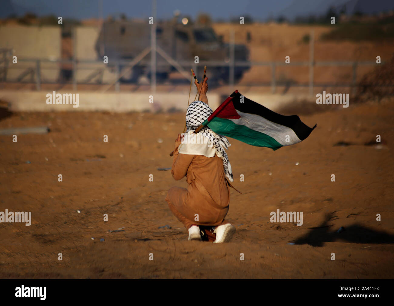 Un manifestante palestino utiliza un tirachinas a arrojar piedras durante una manifestación anti-Israel para poner fin a los años de asedio en la frontera Israel-Gaza en el sur de Gaza. Foto de stock