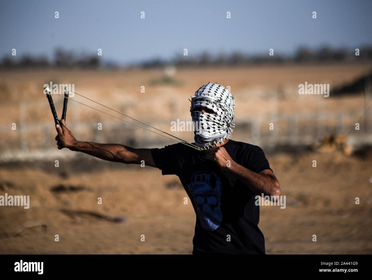 Un manifestante palestino utiliza un tirachinas a arrojar piedras durante una manifestación anti-Israel para poner fin a los años de asedio en la frontera Israel-Gaza en el sur de Gaza. Foto de stock