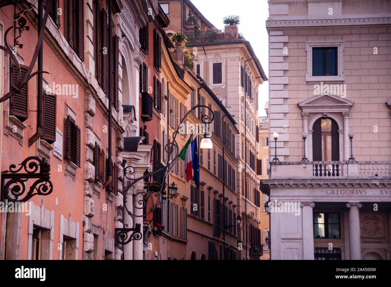 Fachadas de colores cálidos, persianas de madera y detalles arquitectónicos románicos en Roma, Italia. Foto de stock