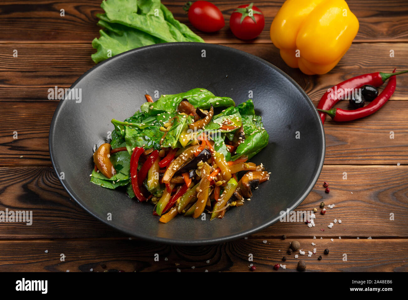 Fried wok verduras: berenjenas, zanahorias, champiñones, calabacín, cebolla  roja, brotes de soja y las hojas de espinacas fritas en salsa teriyaki en  una placa negra en un Fotografía de stock - Alamy