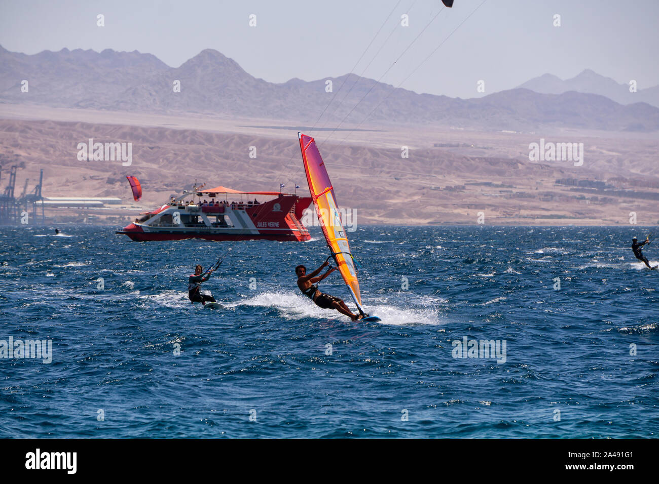 Eilat, Israel - 12 de abril de 2019: Los Aventureros están disfrutando de los deportes acuáticos, el windsurf y el kitesurf, en el Mar Rojo durante un día soleado. Foto de stock