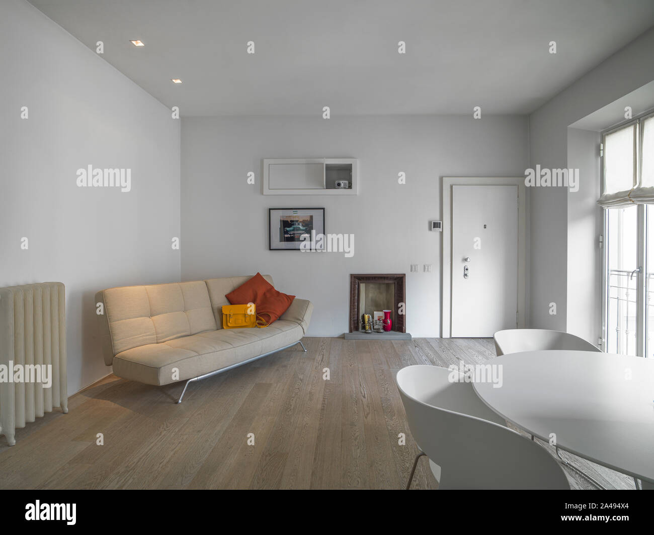 Vista interior de una moderna sala de estar, en primer plano el blanco mesa de comedor con siempre de color blanco, y en fondo la tela beige Fotografía de stock -