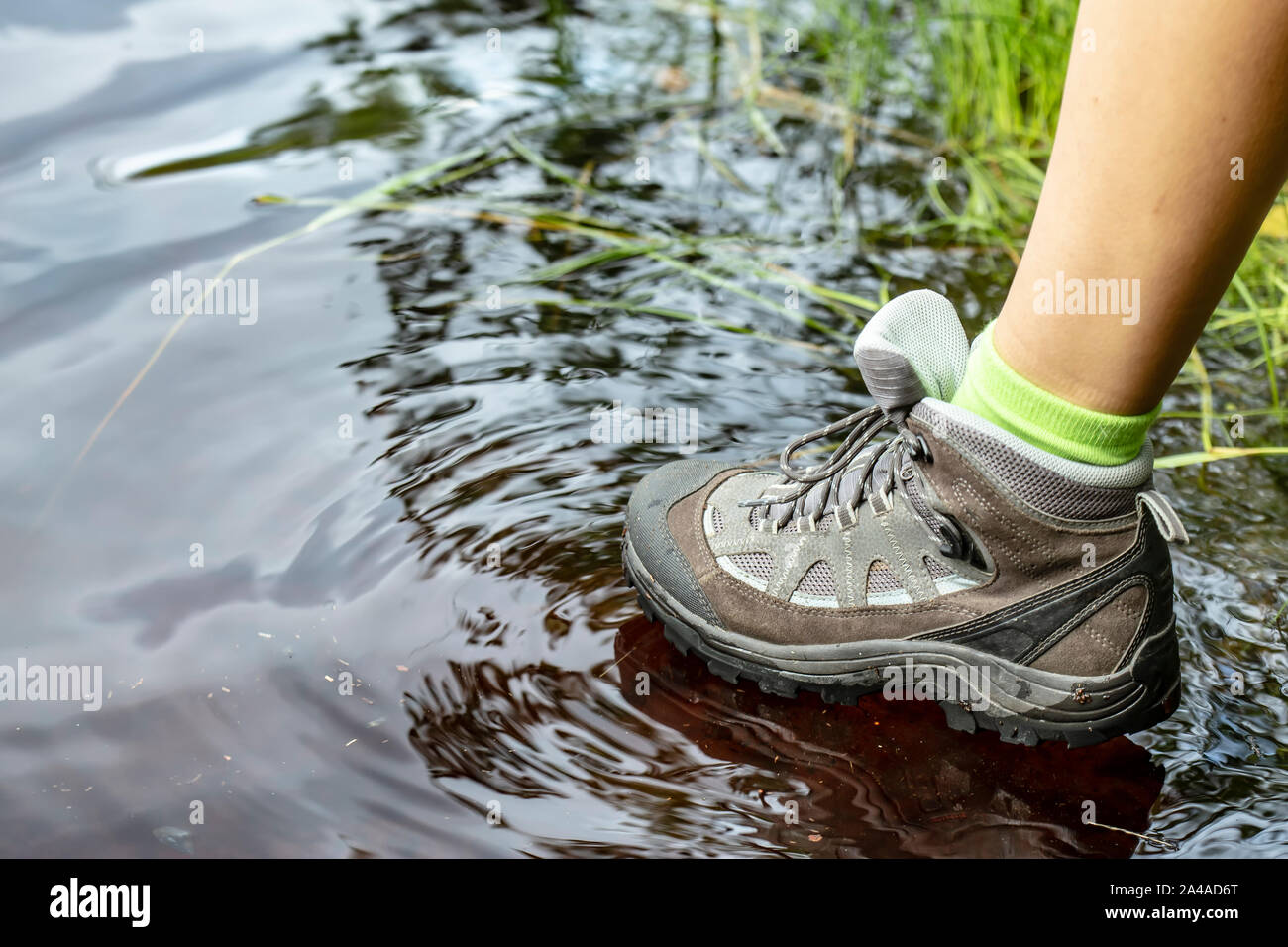 Mujer botas trekking impermeables paseos turísticos través del agua en charcos. Close-up Fotografía de stock - Alamy
