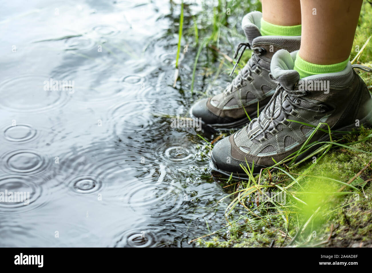 Mujer en botas de trekking impermeables turística está de pie a la orilla  de un lago, justo al lado del agua de la lluvia. Close-up Fotografía de  stock - Alamy