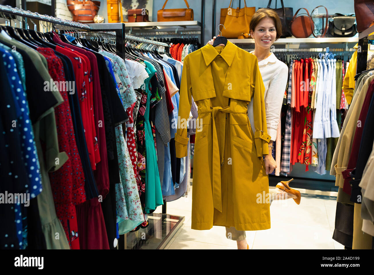 Mujer joven está demostrando impermeable de color mostaza en tienda de ropa  para mujeres Fotografía de stock - Alamy
