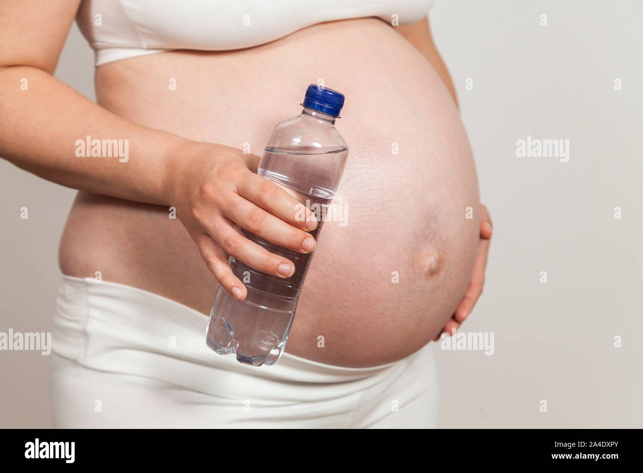Mujer embarazada sosteniendo una botella de agua en la mano Foto de stock