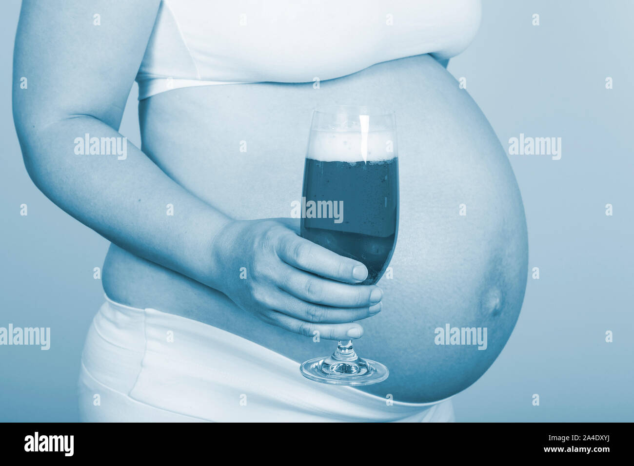Mujer embarazada sosteniendo un vaso de cerveza en la mano Foto de stock