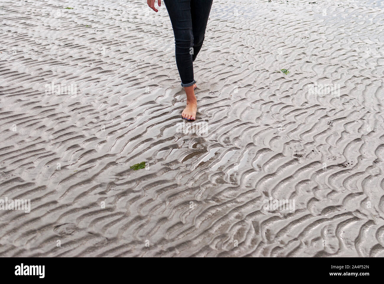 Mujer joven caminando y jugando en la playa de arena y dejar huellas en la playa. Killbrittain, Kilbrittain playa, Irlanda. Foto de stock