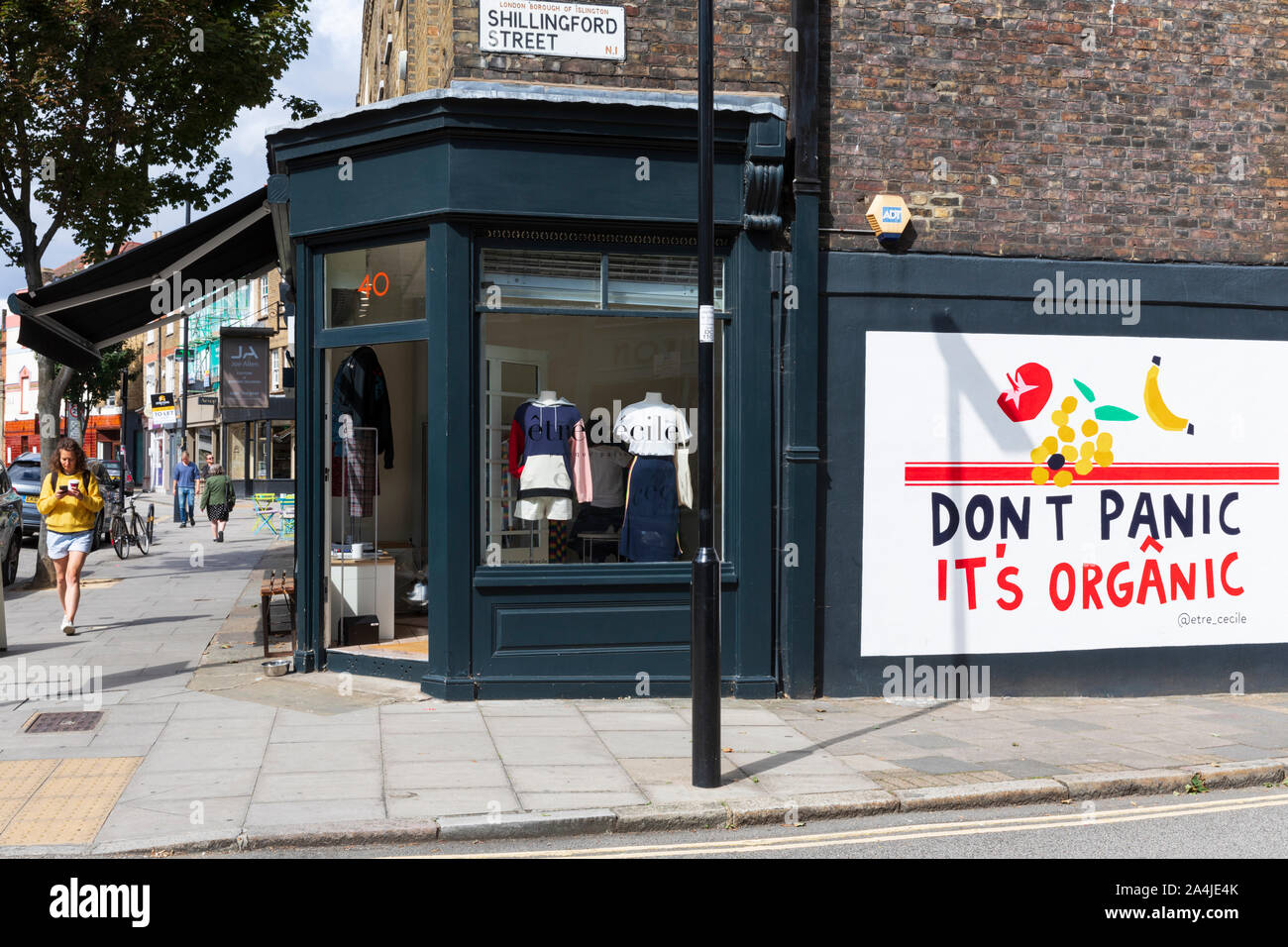 Las tiendas boutique y una que no cunda el pánico es orgánico mural en la esquina de la Calle Cross y Shillingford Street en Islington, Londres, Inglaterra, Reino Unido. Foto de stock
