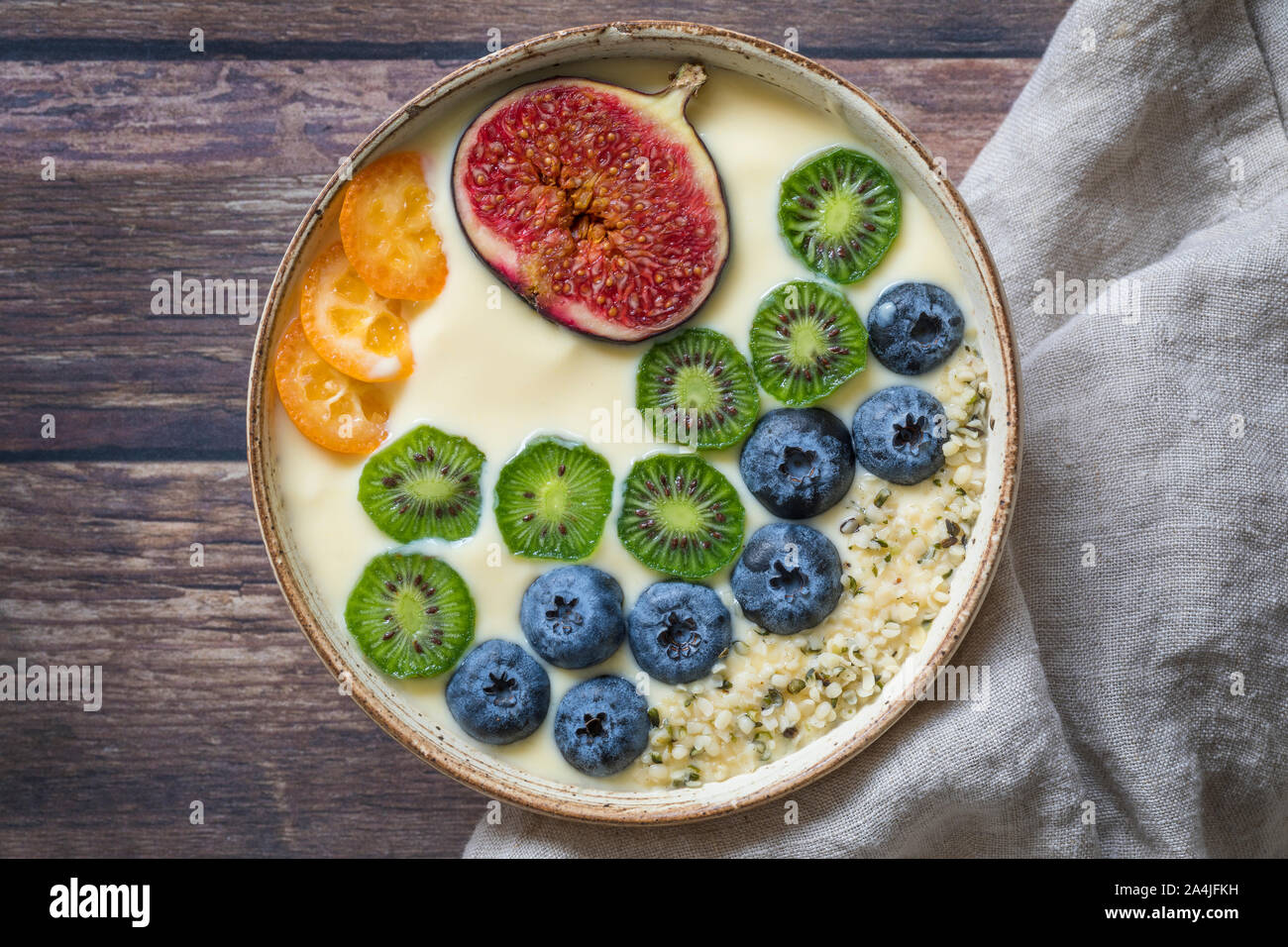 Una fresca y saludable batido de yogur orgánico bowl visto desde arriba,  con una variación de frutas frescas, arándanos, mini kiwis, higos, fruta de  la pasión y kumqu Fotografía de stock -