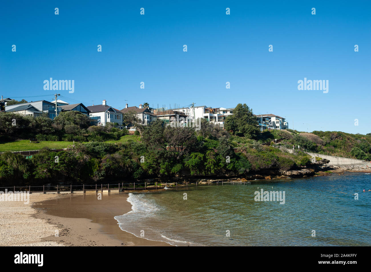 24.09.2019, Sydney, New South Wales, Australia - Vista de Clovelly Playa bajo un cielo azul claro con edificios en el fondo. Foto de stock