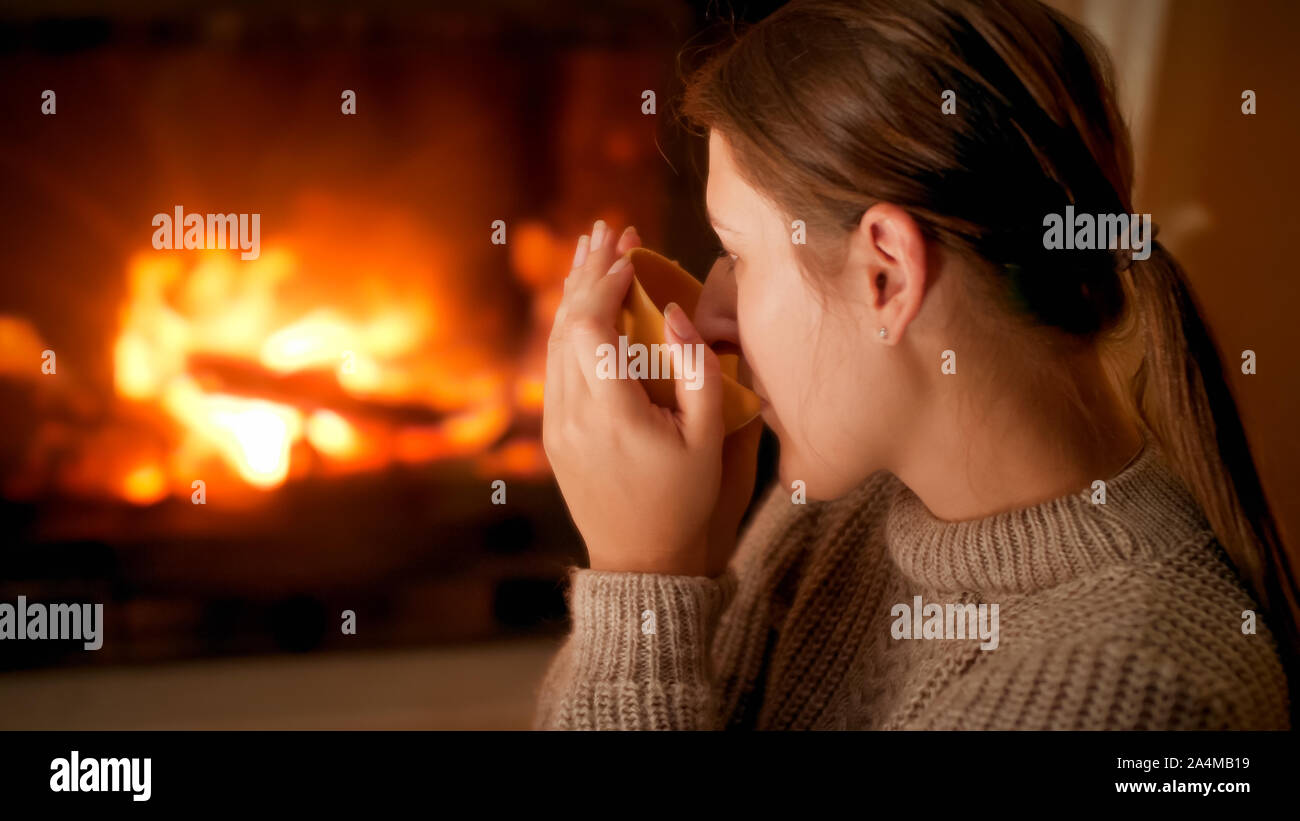 Retrato de mujer joven en el sweater dirnking té y disfrutar de "fuego en  la chimenea en el hogar Fotografía de stock - Alamy