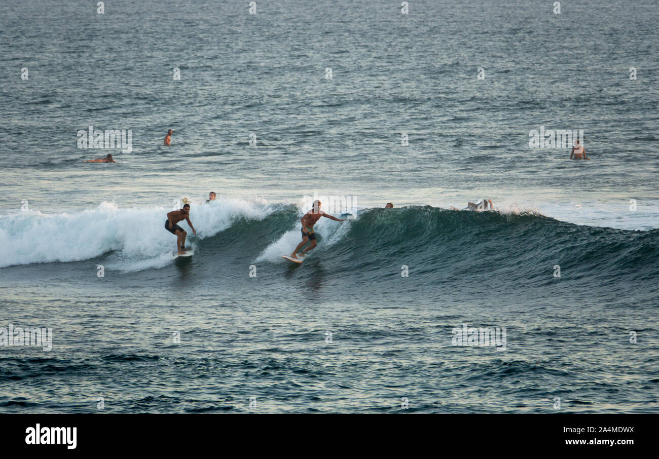 Dos surfistas cabalgando una ola en Canggu playa de Bali, Indonesia Foto de stock