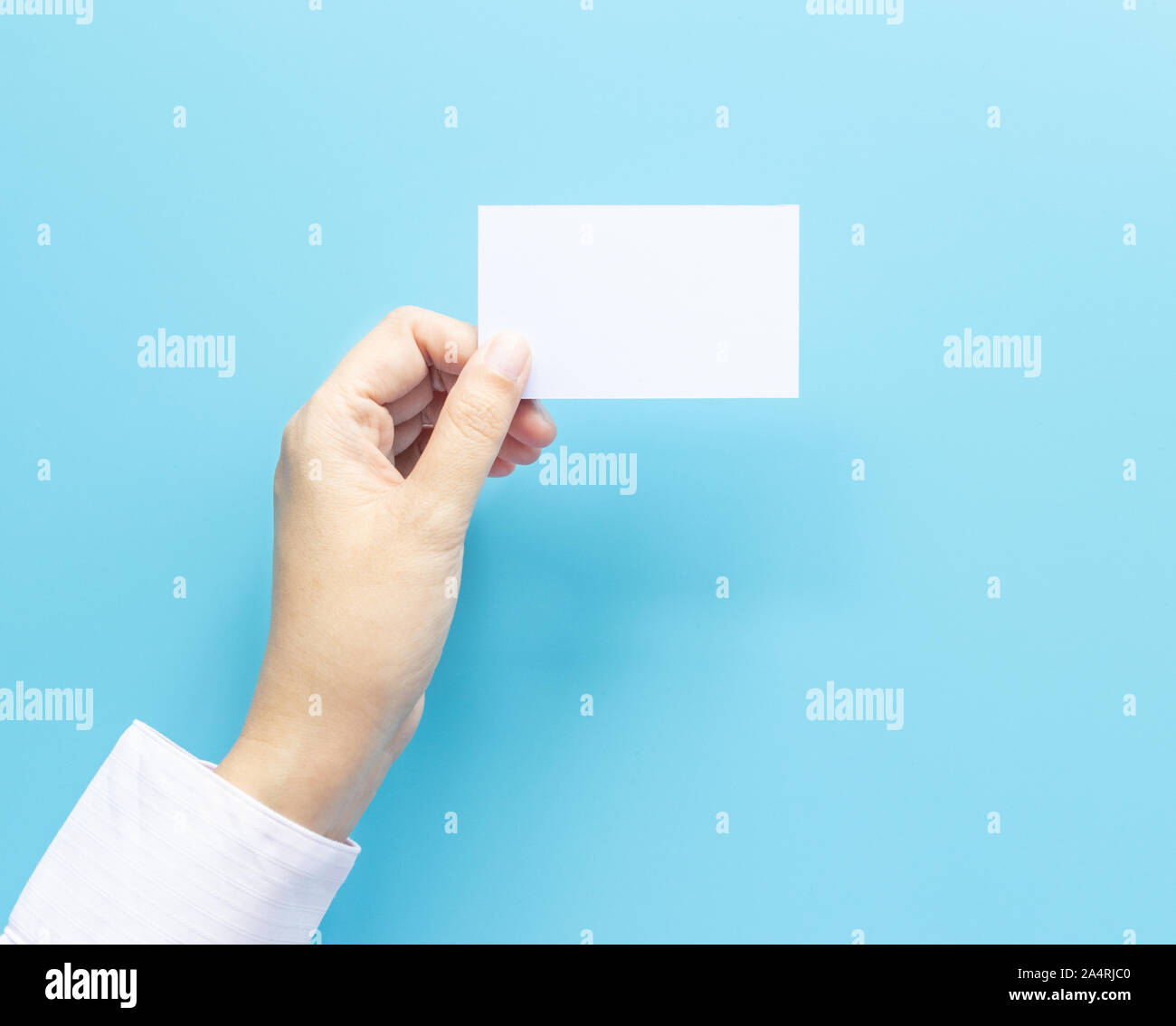 Mujer mano sujetando el nombre de la empresa en blanco cartulina aislado sobre fondo azul con espacio de copia. Foto de stock