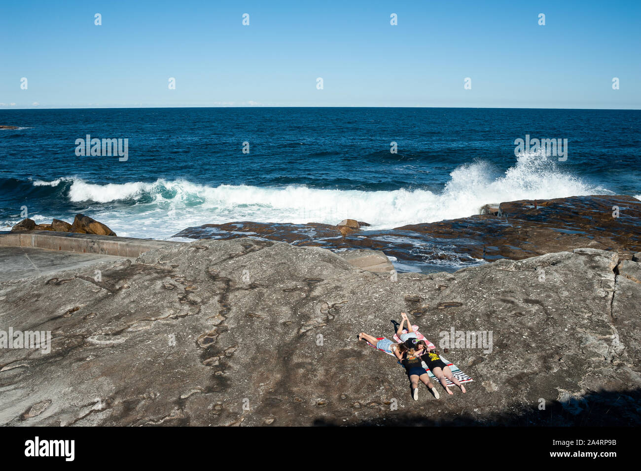 24.09.2019, Sydney, New South Wales, Australia - un grupo de chicas sunbathes sobre los acantilados de Tom Caddy Clovelly punto cerca de la playa. Foto de stock