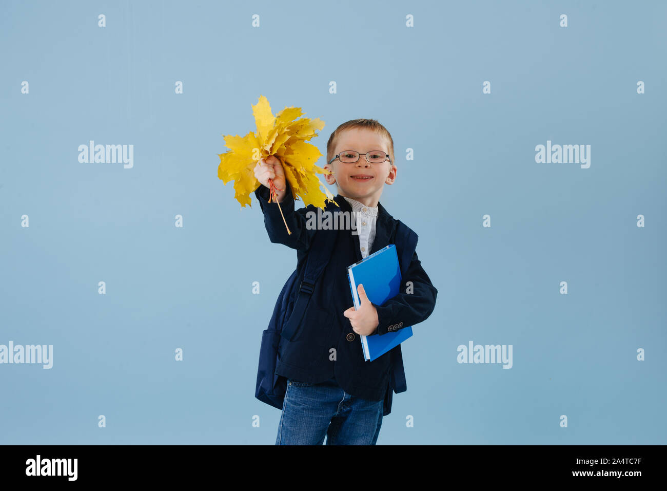 Poco ginger boy en uniforme listo para su primer día en la escuela a través del azul Foto de stock