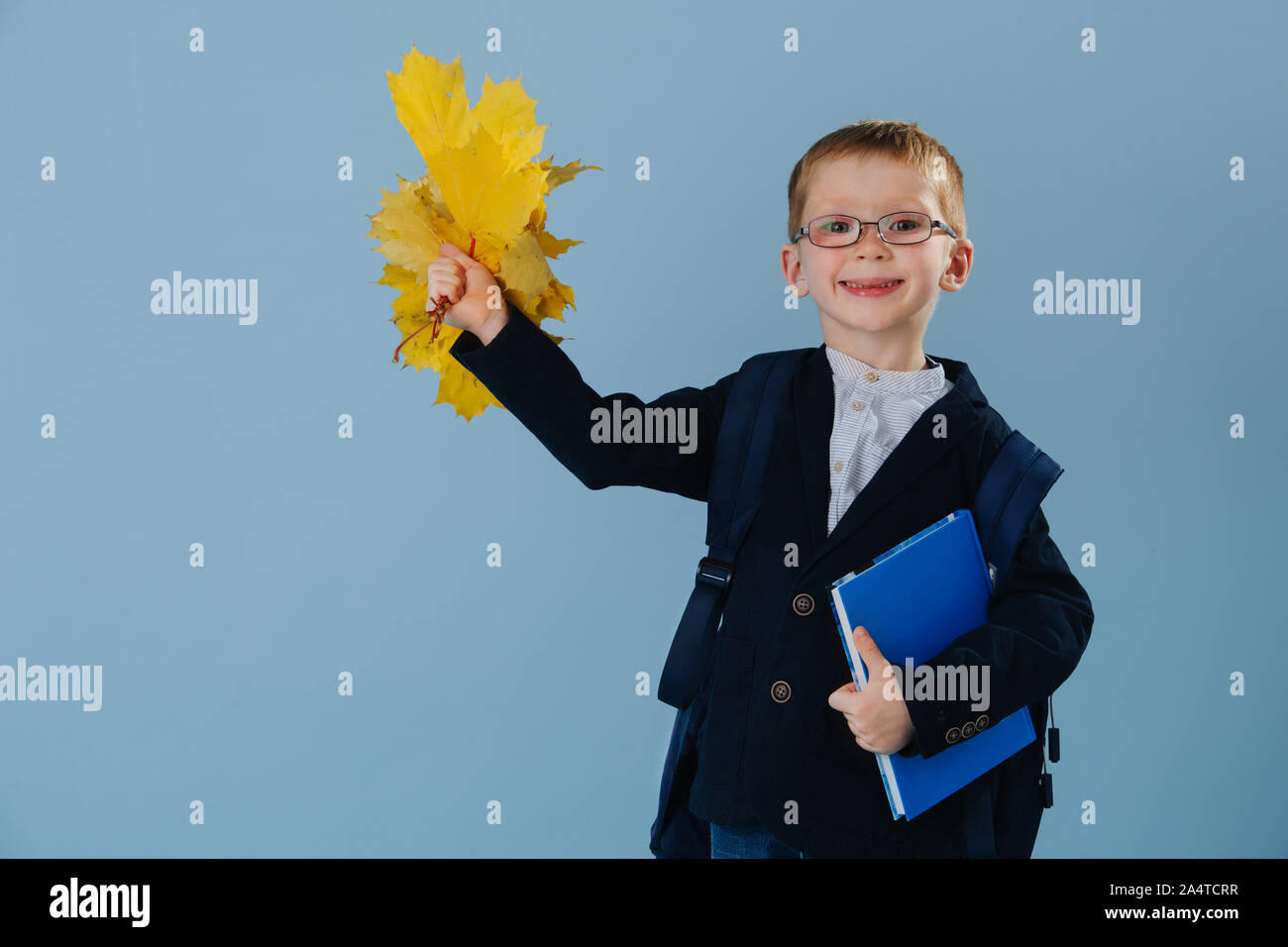 Poco ginger boy en uniforme listo para su primer día en la escuela a través del azul Foto de stock