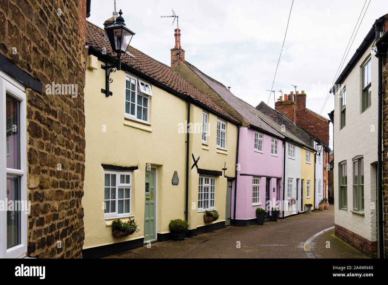 Fila de coloridas casas antiguas pintadas en la angosta calle residencial. El Dean's Street, Oakham, Rutland, Inglaterra, Reino Unido, Gran Bretaña Foto de stock