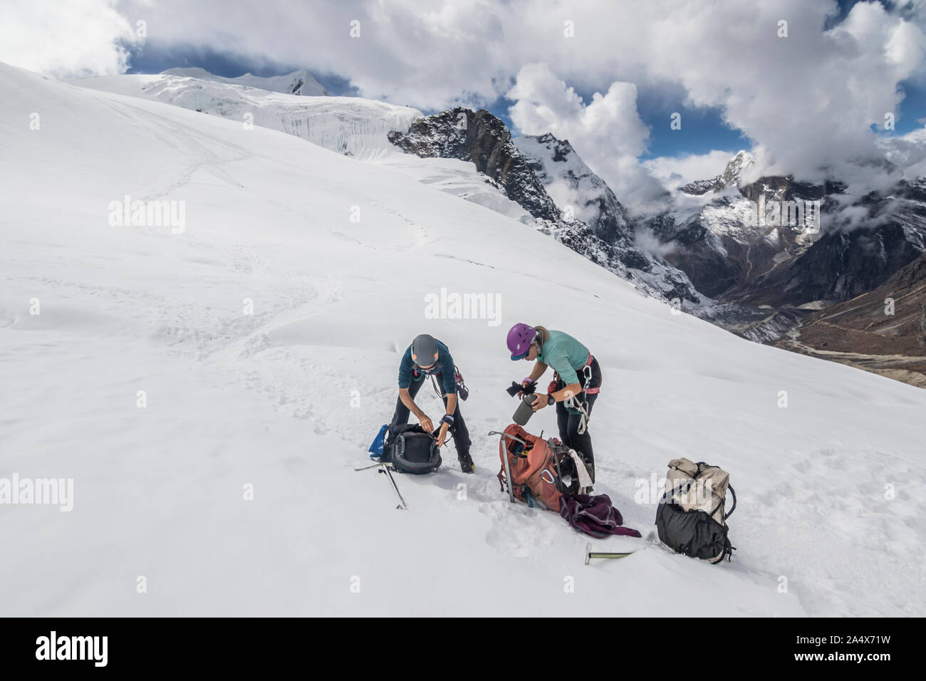 Dos mujeres alpinistas tomar una rotura de engranajes en el glaciar de Mera Peak Foto de stock