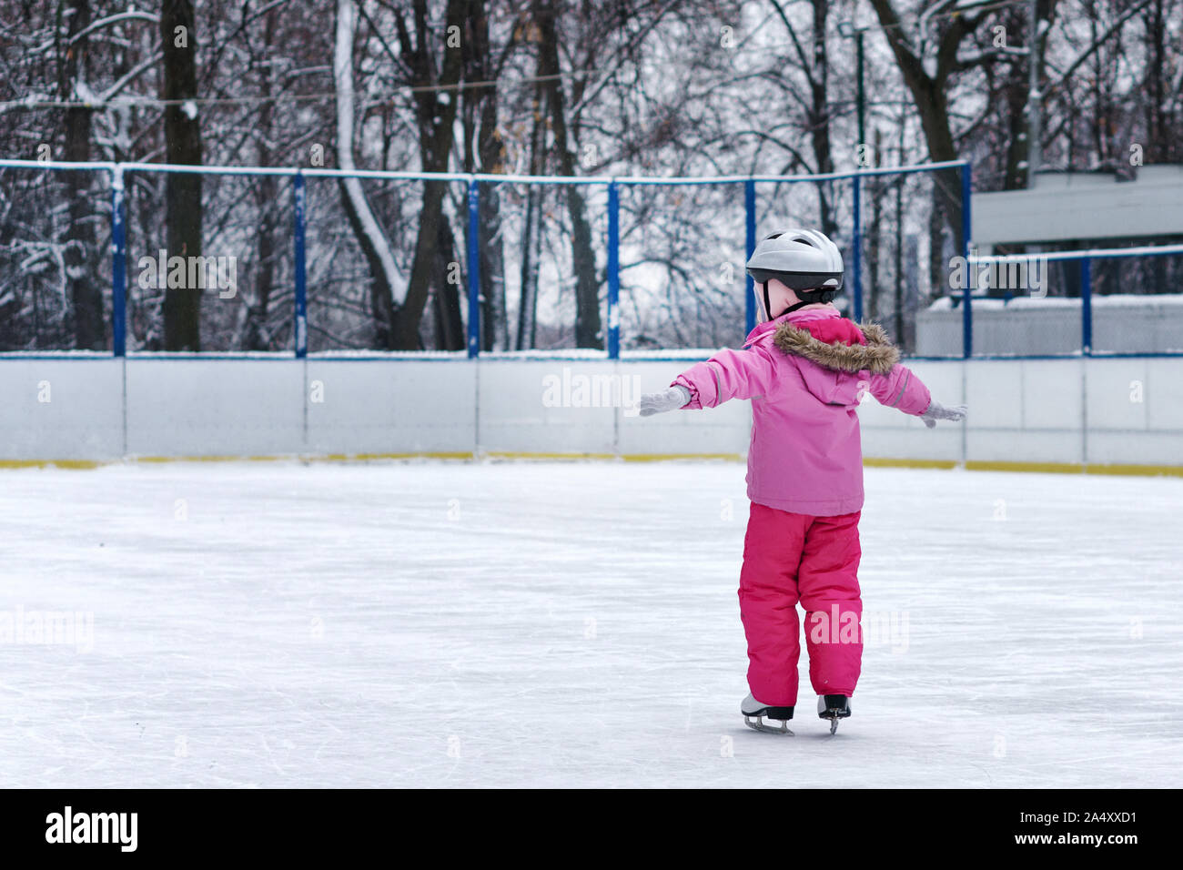 Hermosa niña divirtiéndose en Winter Park, mientras que el equilibrio  patinando en la pista de patinaje sobre hielo. Disfrutar de la naturaleza,  tiempo de invierno. El bebé hace sus primeros pasos en
