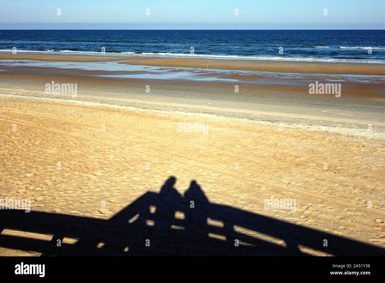 Las sombras de dos personas en un mirador mientras disfrutan de una vista de Ormond Beach en la tarde Foto de stock
