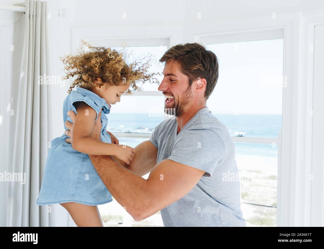 Padre tocando y moviendo hija en casa de playa Foto de stock