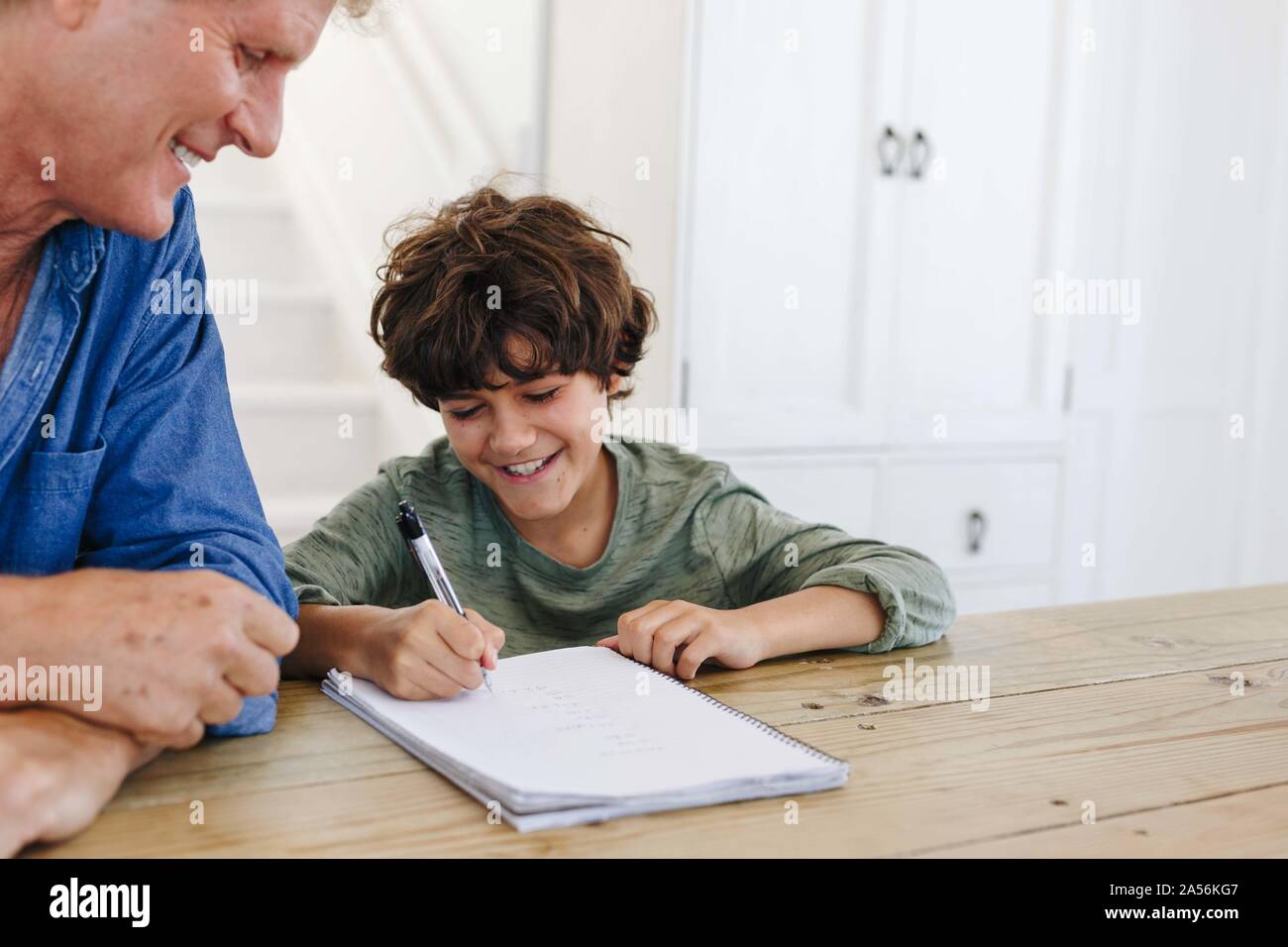 Hijo de padre ayudando con las tareas escolares en casa Foto de stock