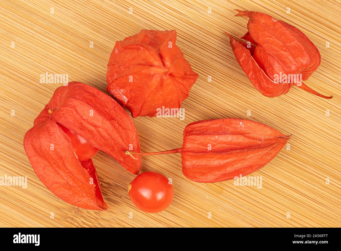 Grupo de cinco physalis flatlay naranja fresca entera en madera ligera Foto de stock