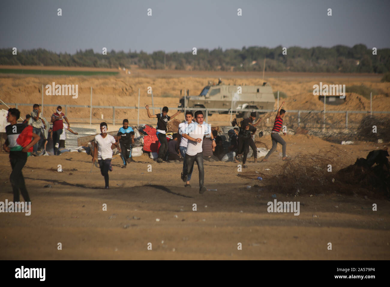La franja de Gaza. 18 Oct, 2019. Los palestinos ejecutar para tomar la cubierta de botes de gas lacrimógeno disparado por las tropas israelíes durante los enfrentamientos en la frontera Gaza-Israel, al este de la ciudad del sur de la Faja de Gaza, Khan Younis, 18 de octubre de 2019. Al menos 69 palestinos resultaron heridos el viernes por disparos de los soldados israelíes durante los enfrentamientos con decenas de manifestantes palestinos en el este de la Franja de Gaza, cerca de la frontera con Israel, dijeron los médicos. Crédito: Khaled Omar/Xinhua/Alamy Live News Foto de stock