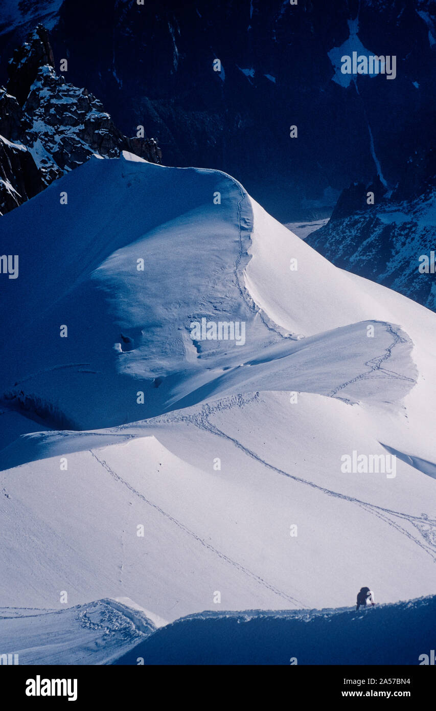 La diminuta figura de un escalador de la Aiguille de Midi, con las montañas de los Alpes más allá Foto de stock