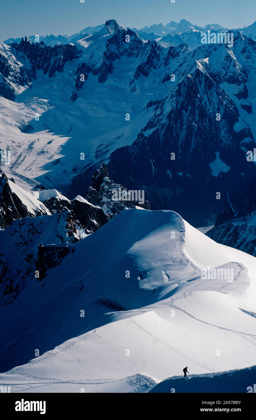 La diminuta figura de un escalador de la Aiguille de Midi, con las montañas de los Alpes más allá Foto de stock