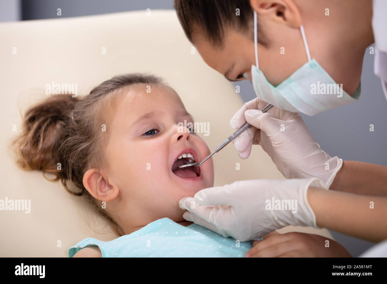 Close Up De Un Dentista Pediátrico Examinando Un Poco Los Dientes De Las Niñas En La Silla 