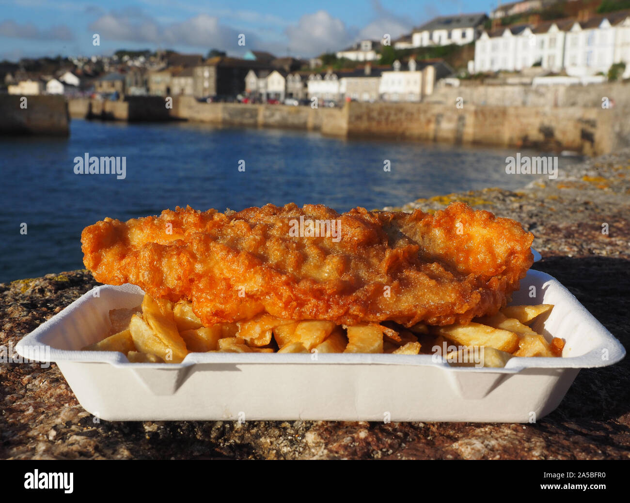Fish and Chips, pescado y patatas fritas tradicional inglés, cerca de la porción de pescado y patatas fritas en Porthleven Harbour, Cornualles, en el REINO UNIDO Foto de stock