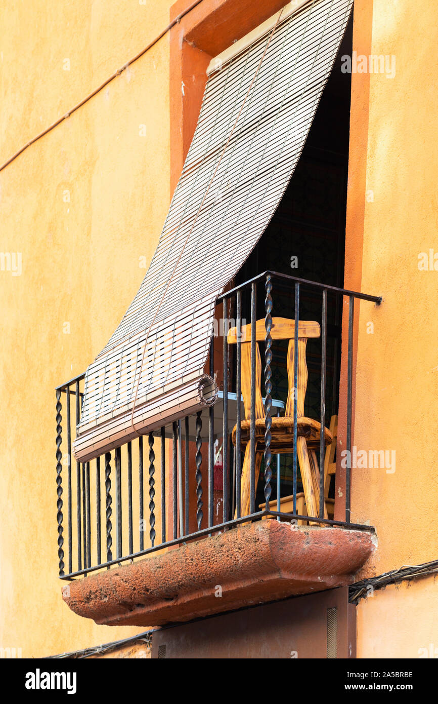 Balcón en un antiguo edificio de piedra en España. Bajar las persianas de  paja para protegerse del brillante sol del verano Fotografía de stock -  Alamy