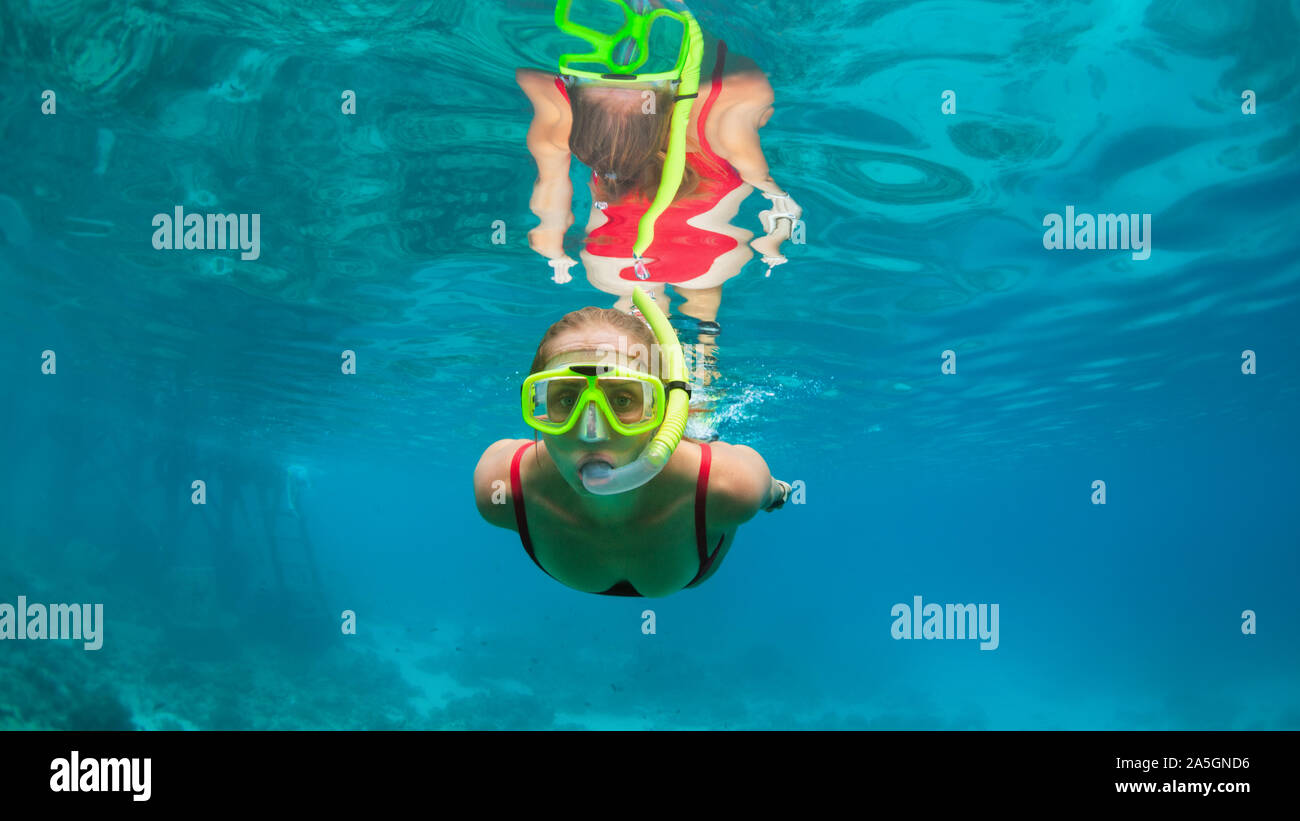 Joven niña alegre en máscara de snorkel y buceo submarino de salto para ver  peces tropicales de arrecifes de coral mar piscina. La actividad de viajes,  deportes acuáticos, deportes de aventura Fotografía